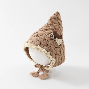 Detail of infant winter knit hat with fish-scale texture and lace trim on a white model