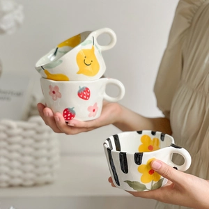 Detailed close-up of hand-painted ceramic mugs featuring cute fruit and flower patterns