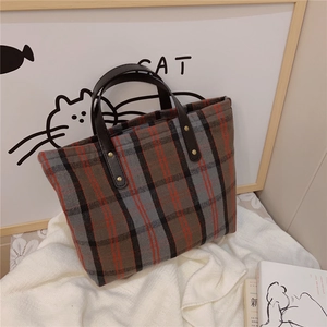 Close-up of vintage plaid tote bag featuring red and black checks with leather handles