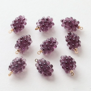 Macro view of nine mini purple resin grape charms with gold rings for DIY jewelry making