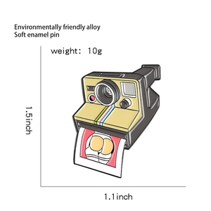 Detail view of retro camera enamel pin with dimensions and cartoon photo detail