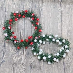 Christmas wreath with artificial snow needles, red and white berries on grey wood background