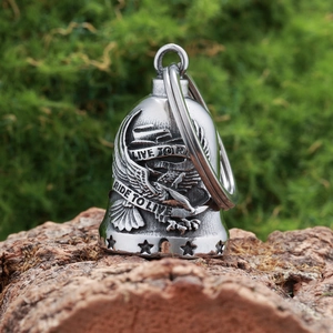 Macro detail of silver eagle guardian bell with Live to Ride engraving on mossy wood
