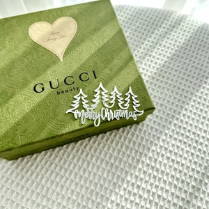 Close-up of white acrylic Merry Christmas cake topper with tree design on green box