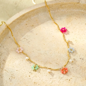 Élégant collier doré avec fleurs en cristal coloré et perles blanches sur plateau