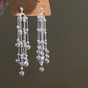 Detailed view of silver layered fringe earrings with long beaded tassels and metallic finish