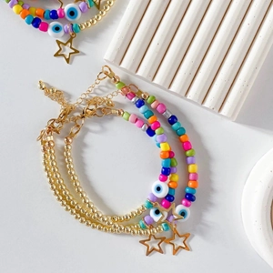 Detail of bohemian gold-plated beaded bracelets with evil eye and star charms
