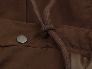 Detail of brown ribbed jacket showing silver metal button and thick woven drawstring