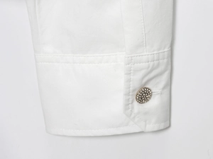Dettaglio del polsino di una camicia in popeline bianco con bottone dorato e strass