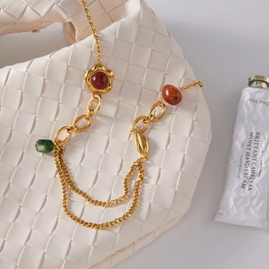 Collana a strati dorata vintage con pietre in resina su una borsa a mano in tessuto bianco