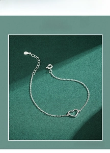 Close-up of minimalist s925 silver heart necklace on deep green textured background