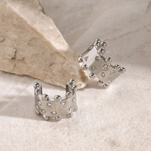 Detail view of silver C-shaped earrings with ball edges and geometric rhinestones
