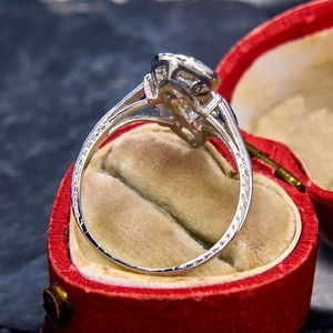 Macro side view of engraved silver ring with round gem in a red velvet jewelry box