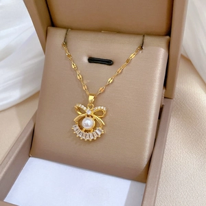 Detail of gold ribbon necklace with pavé crystals and central pearl in jewelry box