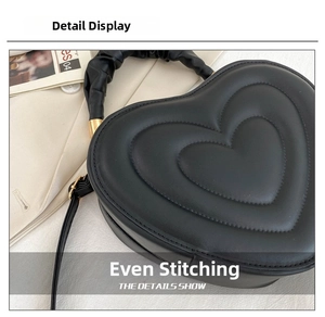 Close-up of black heart-shaped handbag featuring premium embossed stitching details