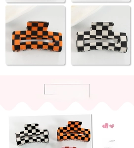 Detail view of checkerboard hair claws in black, white, and orange color contrast