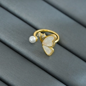 Détail d'une bague papillon dorée avec nacre blanche, perle ronde et petits zircons brillants