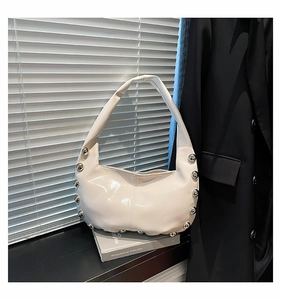 Detail view of cream tote bag with silver studs on smooth PU leather side panels