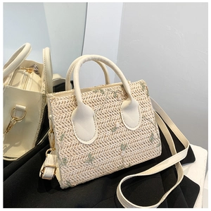 Detail of straw woven handbag with leather handles and golden metal zipper hardware