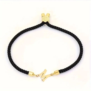 Minimalist black braided rope bracelet with a golden letter M charm and adjustable slide clasp