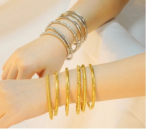 Close-up of stacked gold and silver bracelets in bamboo and beaded styles on a wrist