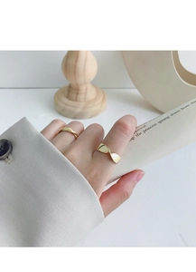 Close-up of gold Mobius twist rings on fingers in a minimalist artistic setting