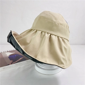 Detail of wide brim beige sun hat with black UV protective lining on a white stand