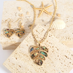Tropical monstera jewelry set with abalone shell inlays on sand stone with starfish