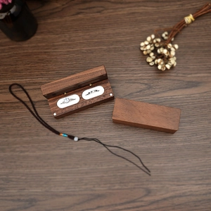 Double slot walnut wood ring box with white velvet lining on dark wooden desk