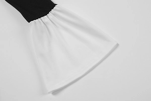 Detail of the black long sleeve dress featuring white flared cuffs with ruffled edges