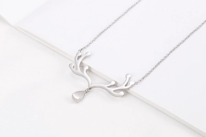 Détail du collier bois de cerf argenté avec pendentif goutte sur fond blanc texturé