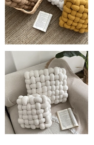 Close-up of woven lamb wool cushions in yellow and white on a cozy sofa setting