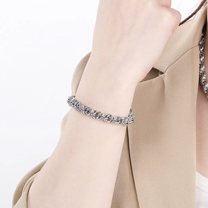 Minimalist silver twist chain necklace and bracelet set worn by a model in a beige suit