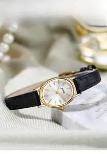 Macro view of gold oval watch case and black crocodile pattern leather strap