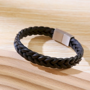 Detail of hand-woven black leather bracelet with silver magnetic clasp on wood