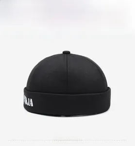 Close-up of black cotton brimless docker hat featuring white side letter embroidery