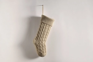 Close-up of beige cable knit Christmas stocking with textured patterns and hanging loop