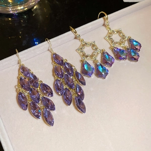 Macro shot of purple crystal leaf drop earrings on a pink velvet jewelry tray
