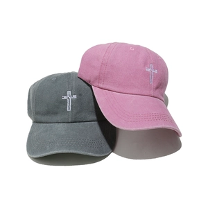 Detail of pink and grey washed cotton baseball caps with embroidered Jesus cross design