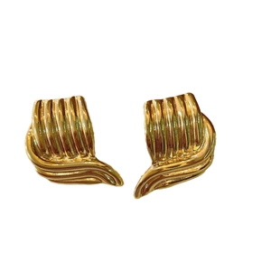 Boucles d'oreilles vintage dorées festonnées avec motif ondulé sur fond blanc