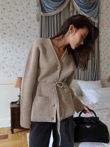 Elegant beige V-neck knitted cardigan with drawstring waist and pockets on a model