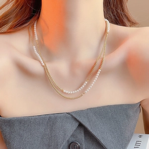 Gros plan d'un collier double épaisseur en or avec perles sur le cou d'un mannequin