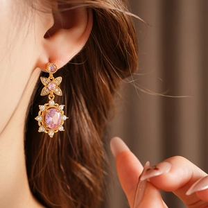 Close-up of vintage golden bow earrings with oval pink zircon worn by a model