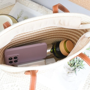 Detailed interior of woven tote bag showing large capacity with zipper and leather strap