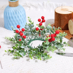 Christmas candle ring with red berries and green leaves on a textured white fabric base