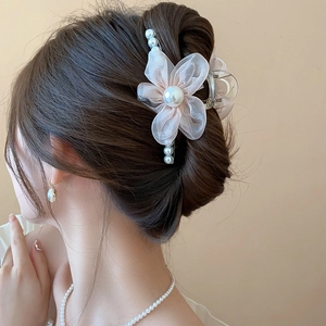 Detail of pink silk flower and pearl hair claw clip worn on a low bun hairstyle