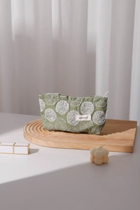 Close-up of floral embroidery on green cotton linen makeup bag with H&R BAG logo label