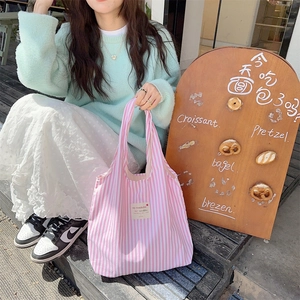 Close-up of pink and white striped canvas tote bag with woven logo label