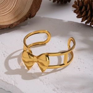 Détail d'un bracelet jonc avec nœud plaqué or 18 carats sur pierre blanche et pomme de pin