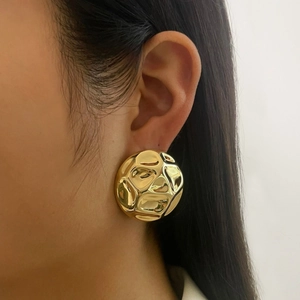 Close-up of woman wearing large hammered gold-plated chunky hollow hoop earrings